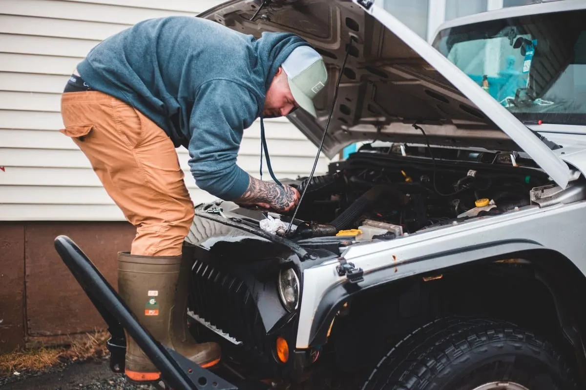 Mobile mechanic working on a car engine at a customer's driveway